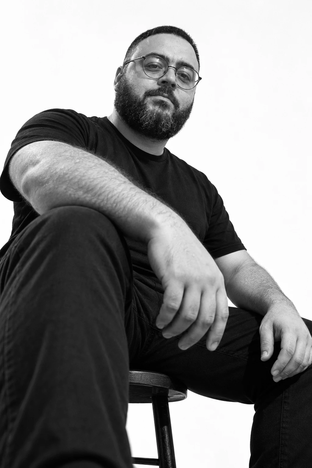 Black-and-white low-angle portrait of Lamek Felix wearing round glasses