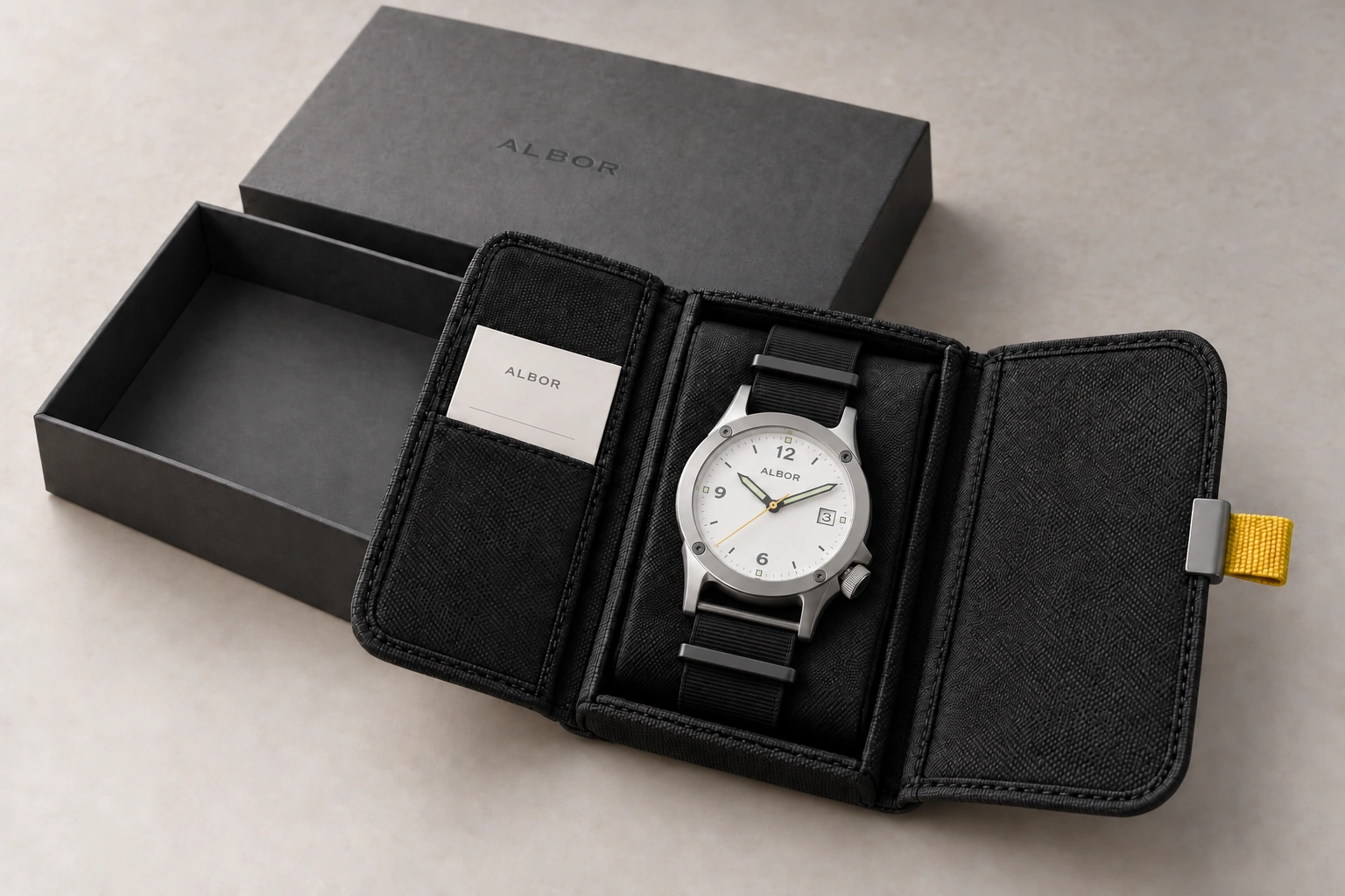 Road Kit concept: graphite presentation box and open reusable black textile watch pouch with yellow pull tab with the current integrated-lug ALBOR watch